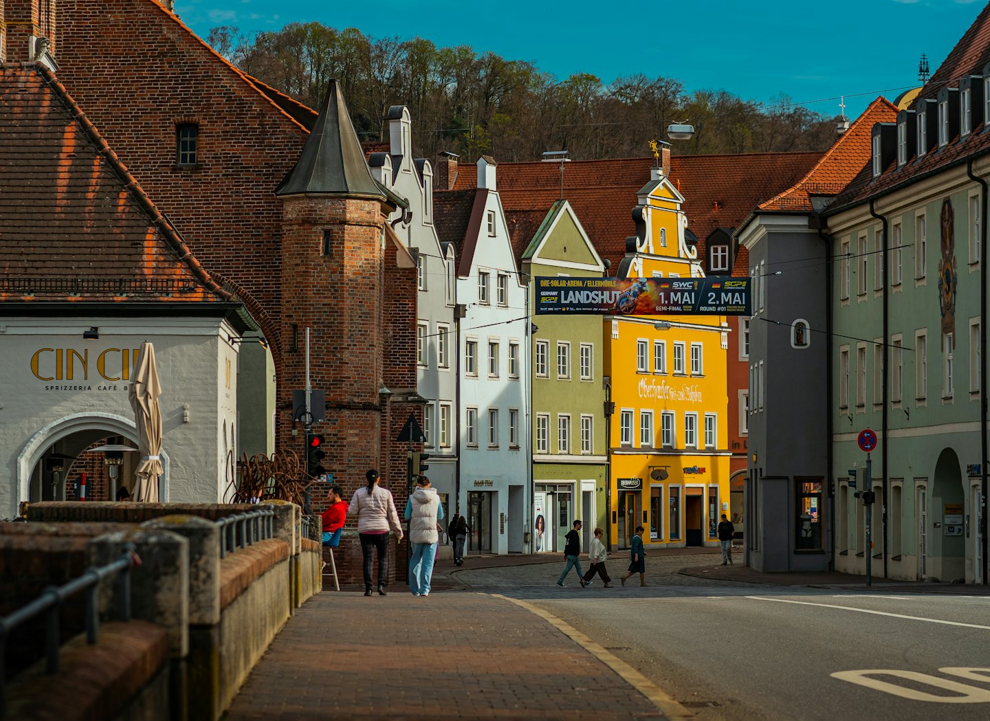 Voetgangers lopen door een Europese stadsstraat langs historische gebouwen.